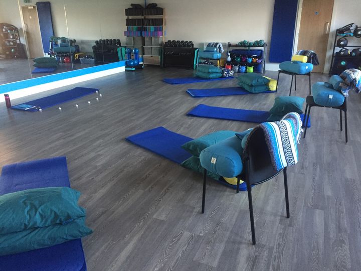 a yoga class set up with bolsters, pillows, blankets etc to aid relaxation